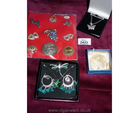 A box containing nine brooches, a butterfly pendant in box, a necklace, earrings, a butterfly brooch, all blue stone boxed an