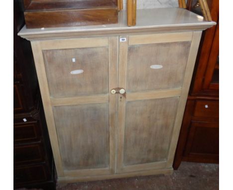 A 3' 10" vintage part stripped mixed wood cabinet with two drawers and shelves enclosed by a pair of panelled doors, set on p