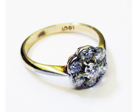 A marked 18ct. flowerhead ring, set with seven diamonds
