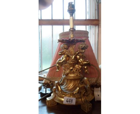 A cast gilt brass table lamp with bacchanalian putti decoration, with shade