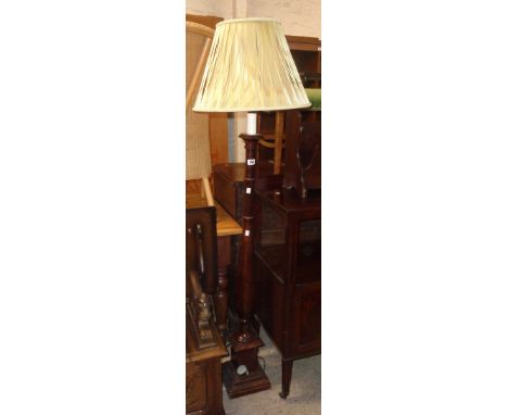 A 20th Century stained oak torchère style standard lamp and shade, set on turned pillar and pedestal base
