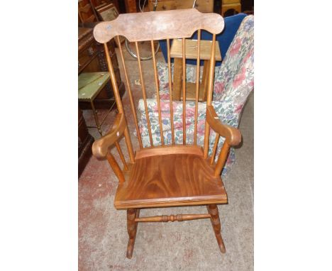 A 20th Century mixed wood high stick back rocking chair with solid laminated seat and ring turned supports