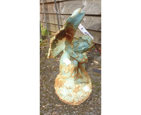 A cast iron garden angel seated on a ball