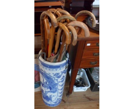 A large ceramic stick stand containing assorted walking canes and umbrellas