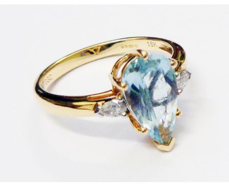 A hallmarked 750 14k gold ring, set with central pear cut Paraiba tourmaline and flanking similarly cut diamonds