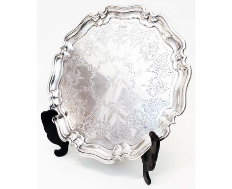 A 12 1/2" diameter silver salver with shaped cast rim, engraved decoration and central initial "H", set on nautilus shell pat