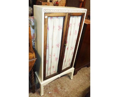 A 23 3/4" early 20th Century book cabinet with later painted finish, the glazed doors replaced with material curtains, set on