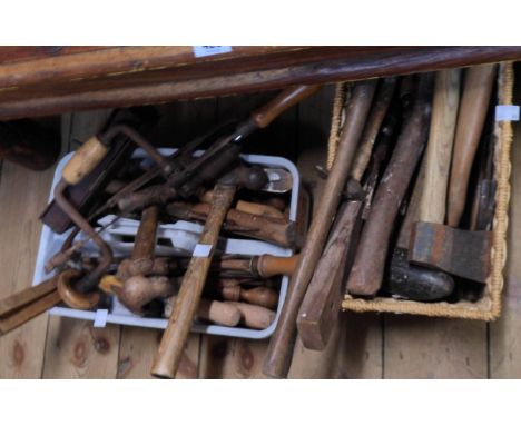 A basket and tool carrier containing assorted old tools, hammers, axes, screwdrivers, saws, etc.