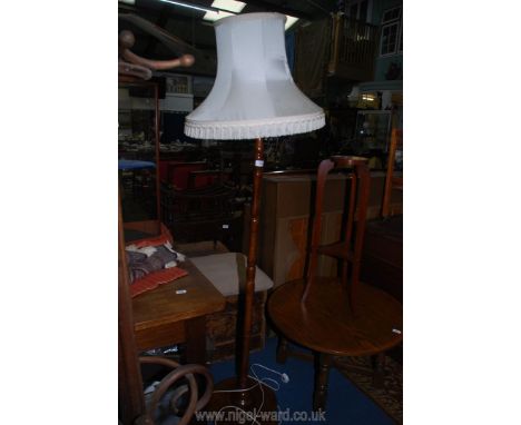 A wooden standard lamp with cream fringed shade (tear to shade) standing on 3 flat round feet.