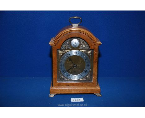 A ''Tempus Fugit'' mantle Clock by Elliott London, with Roman numerals and mask detail around the face, carrying handle to to