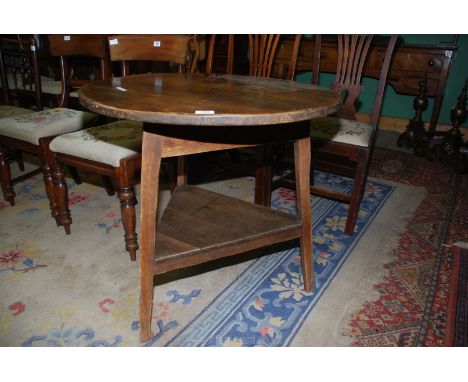 An Oak Cricket Table, the legs united by a lower shelf, 30'' diameter, 28 1/2'' high