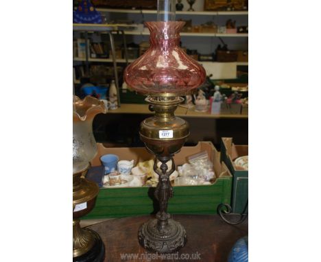 An unusual Oil lamp on cast metal base in the form of a lady with brass reservoir and pale cranberry glass shade, 26 3/4" hig