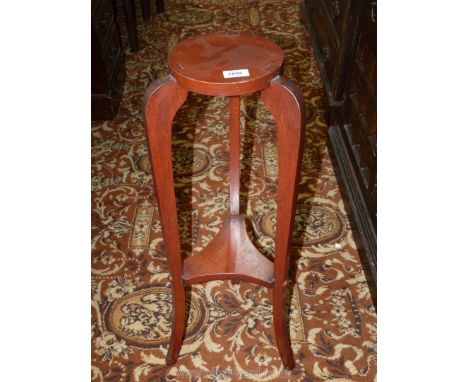 An Oak Jardiniere Stand standing on shaped legs united by a tricorn lower shelf, the top 7 1/2'' diameter x 31 1/2'' high.