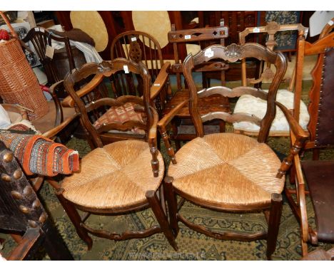 A pair of unusual seagrass seated open armed Carver Chairs having ladder backs and top rails with a carved shell motif.
