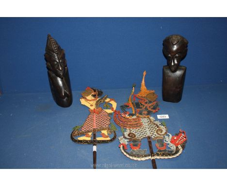 A pair of shadow puppets of a girl and a boy, one arm missing on each puppet. Together with a pair of wooden African figures.