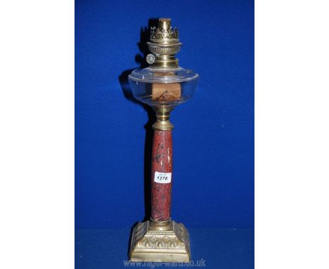 An Oil lamp on square brass bass, marbled effect stand, clear glass reservoir, no shade or chimney, 19" tall.