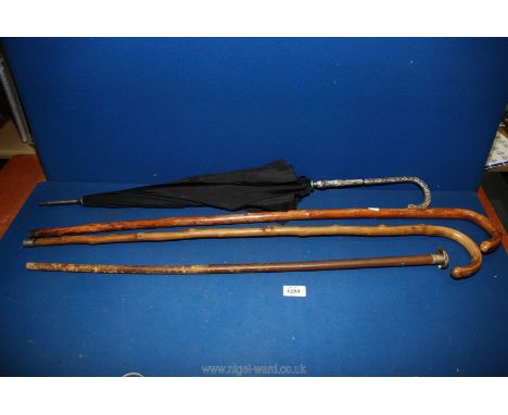 Two wooden walking canes, a dented metal knop walking stick and a white metal handled umbrella.