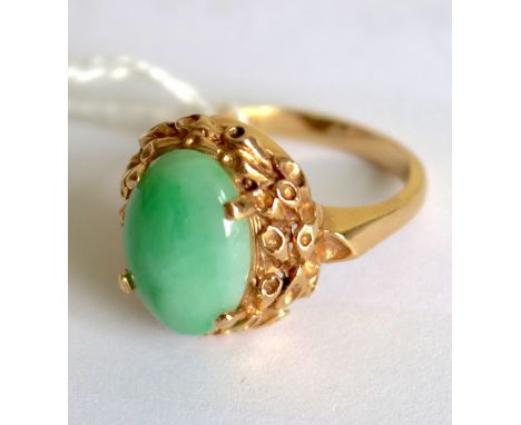 A CHINESE APPLE GREEN JADE RING IN A 14 CARAT GOLD SETTING