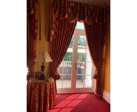 10 sets of luxurious looking gold curtains with a red foliate design and duel coloured tie backs along with striped swags and