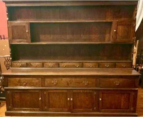 A George III revival oak dresser, moulded dental pediment on three tier plate rack shelves, flanked by twin panel cupboards o