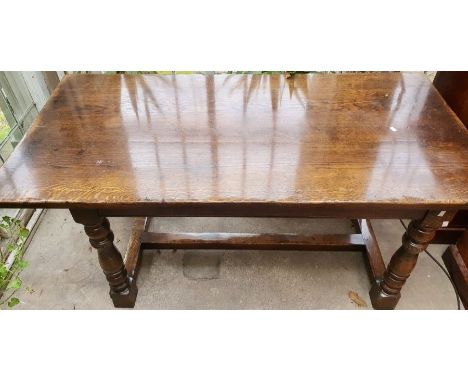 A 20th century oak refectory table, in a 17th century manner, single plank top, raised on a turned supports united by stretch