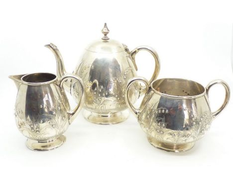 A Victorian aesthetic movement silver three piece tea service engraved and repousse with lily of the valley comprising teapot