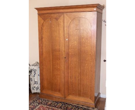 A Victorian oak linen press/wardrobe, circa 1870, moulded cornice above two arch shaped panel doors, enclosing a cylinder clo