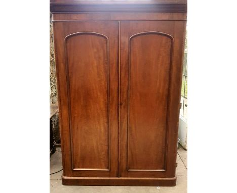 A Victorian mahogany wardrobe, circa 1860, curved moulded pediment above two panel arch moulded doors, enclosing a clothe han