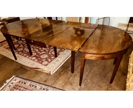 A George III mahogany demi lune end dining table, circa 1800, comprised of a pair of demi-lune end tables united by a twin ga