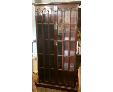 A Chinese hardwood glazed display cabinet, moulded outswept cornice above arch glazed inlay doors, enclosing four glass shelv