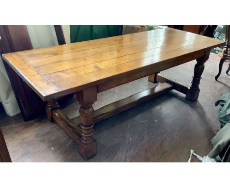 A 20th Century oak refectory table, six plank top with cleated ends, raised on turned on block supports, united by a floor st