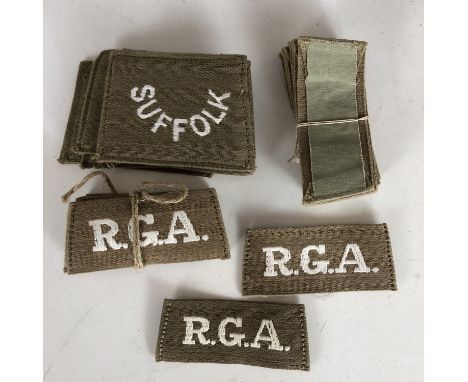 A quantity of original un-issued Great War British Army slip-on cloth shoulder titles, Royal Garrison Artillery and Suffolk R