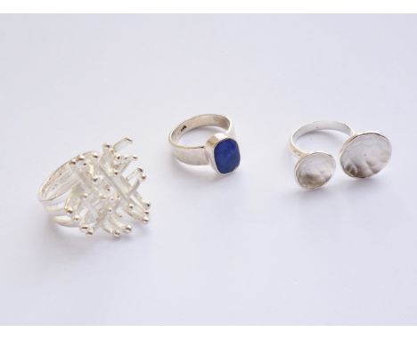 Three contemporary white-metal artisan rings, including one open ring with cusped and planished face, 22.3g