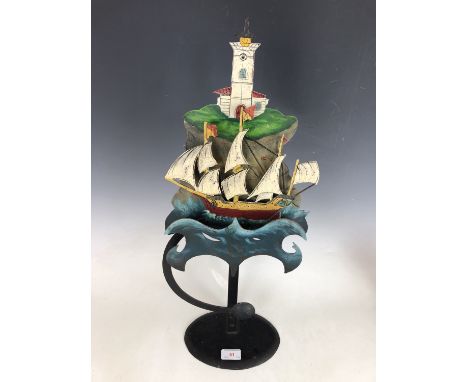 A vintage tinplate oscillating sculpture, modelled in the form of ship bobbing in the waves at the foot of a light house, 59 