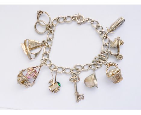 A vintage white-metal curb-link charm bracelet and charms, the latter including a pendant oil lamp, railway lantern, soda syp