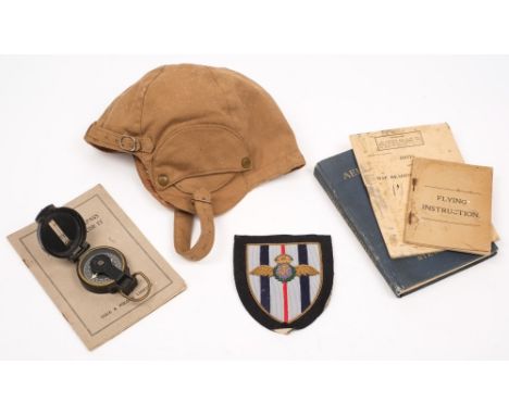 A Royal Flying Corps blazer badge together with a canvas flying helmet:, together with several flying manuals, a compass and 