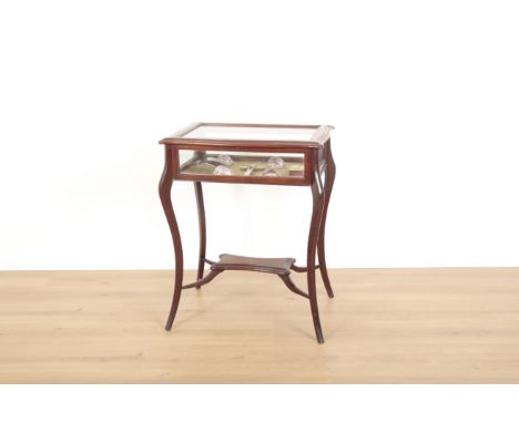 AN EDWARDIAN MAHOGANY BIJOUTERIE TABLEof shaped rectangular outline, the glazed lifting top enclosing fabric lined interior, 