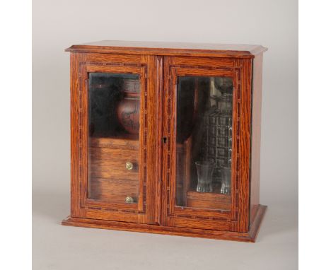 AN OAK SMOKER'S COMPANIONEdwardian, the two glazed doors before shelving to the left-hand side for a later terracotta 'Etrusc