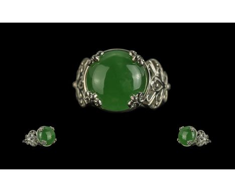 Jade Solitaire Ring, a round cut jade cabochon, held in place by four, fancy, scrolled claws, between two Art Nouveau style, 