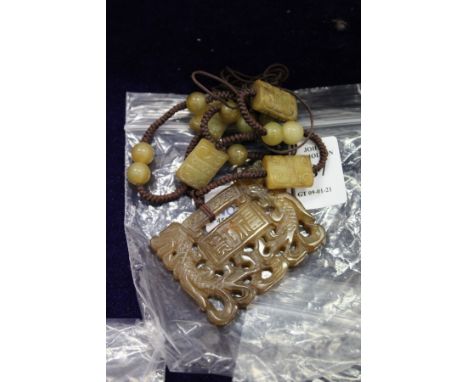 A Chinese carved jade amulet suspended on a cord mounted with jade beads.