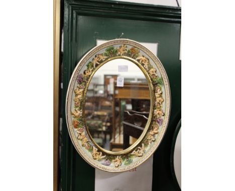 A Capodimonte porcelain mirror, the frame decorated with cherubs.