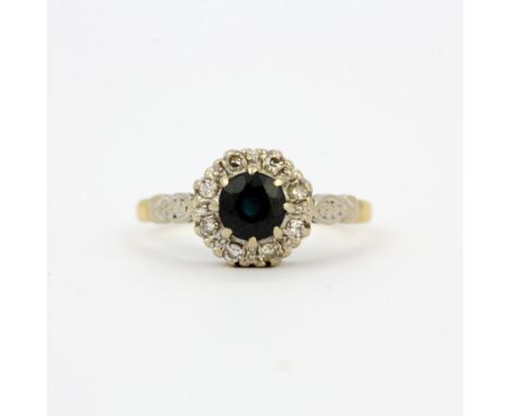 An 18ct yellow and white gold cluster ring set with a sapphire and diamonds, ring size R.5. Approx. 4.2gr.