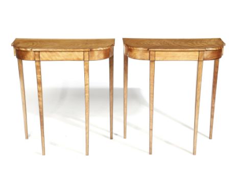 A pair of satin veneered console tables in George III style, inlaid with ebonised stringing, each with a breakfront top, on t