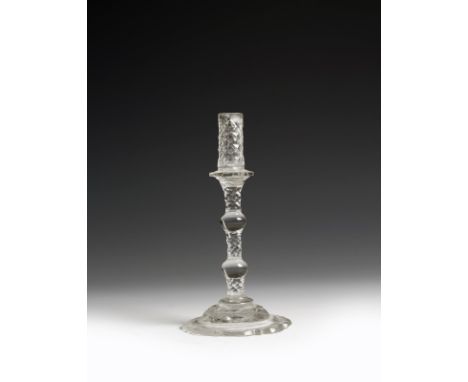 A George III cut glass taperstick, with scale decoration, the petal drip-pan above a twin knopped stem and on a domed lobed f