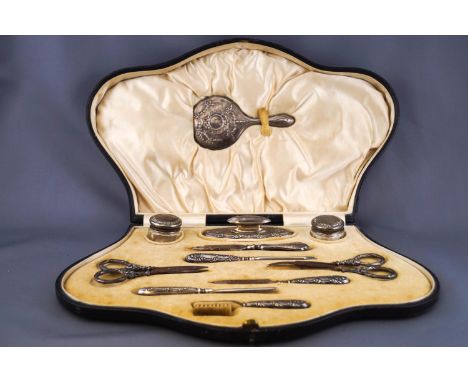 A cased silver eleven piece manicure set comprising hand mirror, buffer, parer, brush and other items, Birmingham 1913 one it