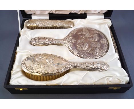 A cased silver four piece dressing table set, comprising two brushes, a hand mirror and comb, decorated with the Reynold's An