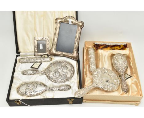 TWO BOXED SILVER VANITY SETS AND TWO SILVER PHOTO FRAMES, the vanity set comprising of a hair brush, hand held mirror, clothe
