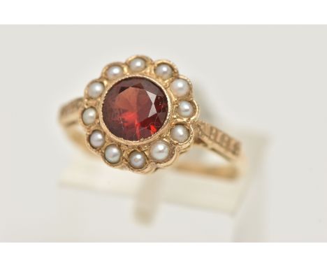 A YELLOW METAL GARNET AND SPLIT PEARL CLUSTER RING, of a circular form set with a central circular cut garnet, milgrain colle