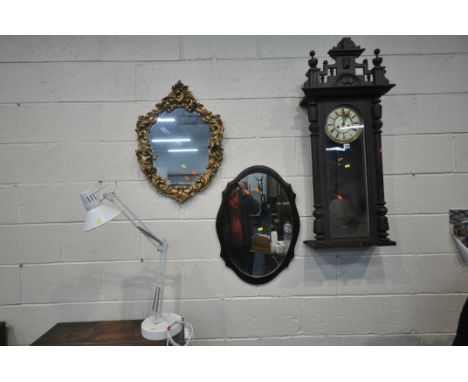 AN EARLY 20TH CENTURY MAHOGANY WALL CLOCK, with shaped crest and twin finials, the arched glass door enclosing an 8 inch bras