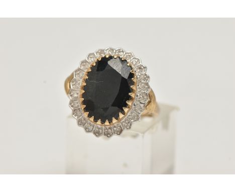 A LARGE 9CT GOLD SAPPHIRE AND DIAMOND CLUSTER RING, of an oval form, set with a central oval cut deep blue sapphire, claw set
